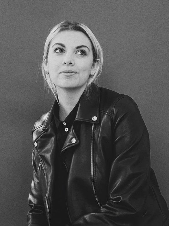 woman looking up and soft smiling wearing a leather jacket