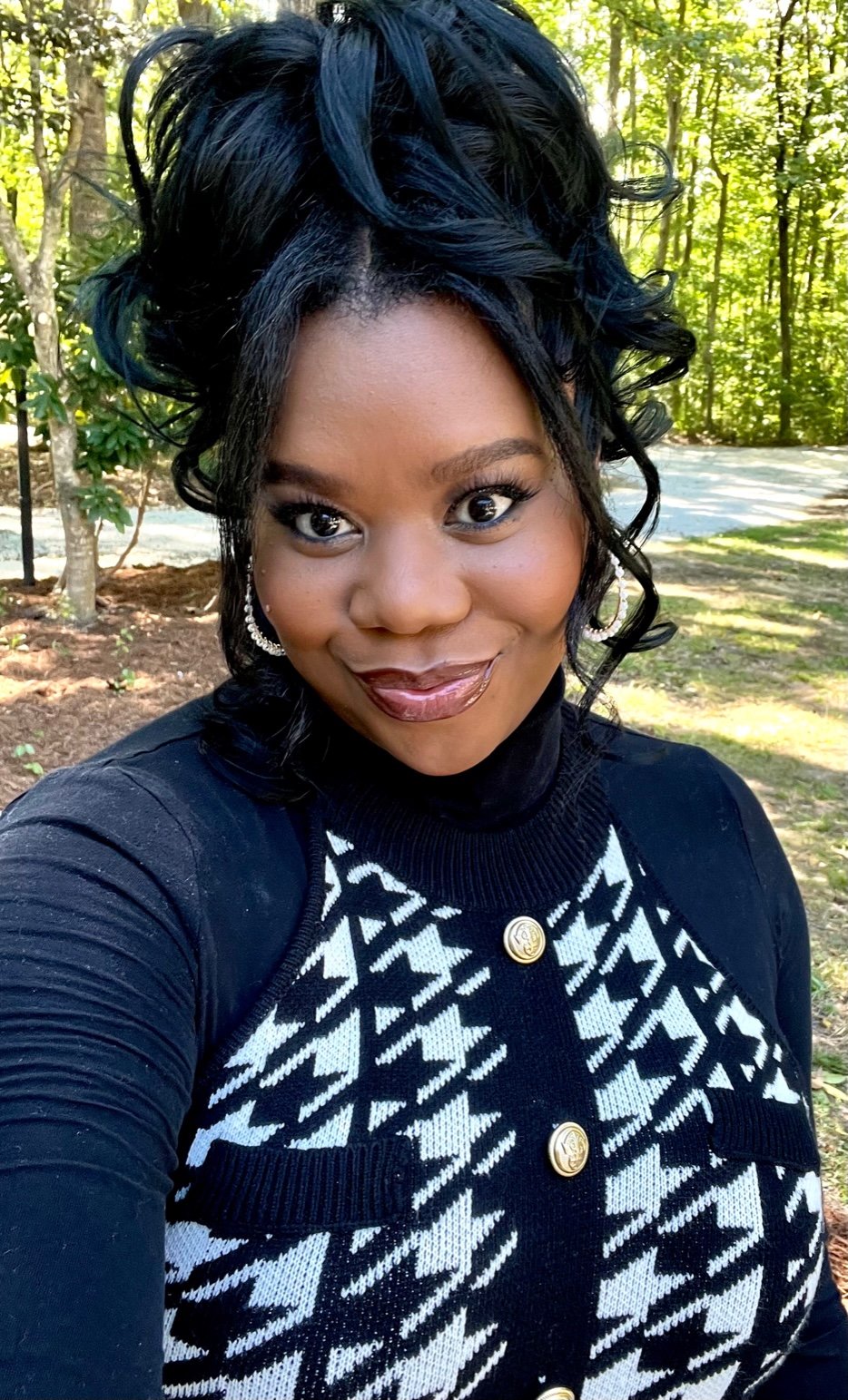 woman with her hair in an updo soft smiling while wearing a houndstooth sweater